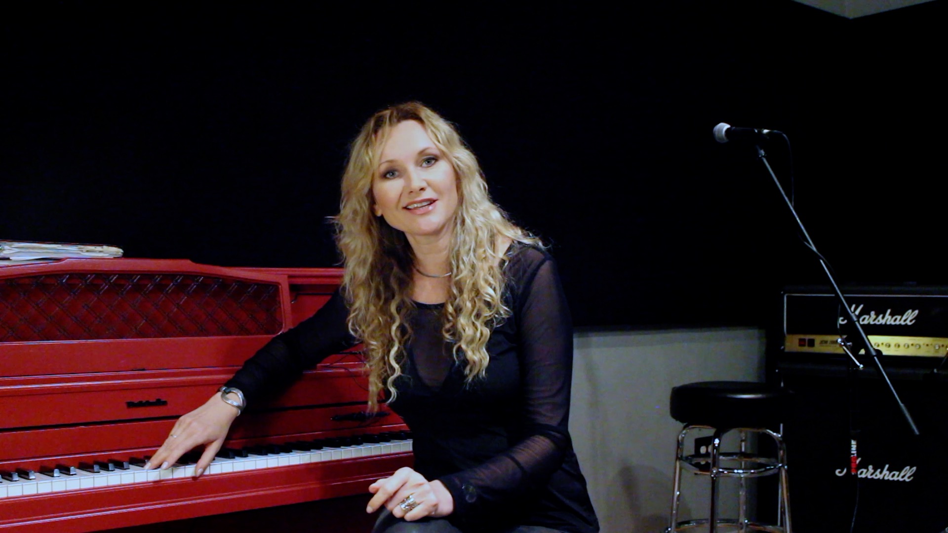 Juliana Polansky seated at a red upright piano in a rehearsal room