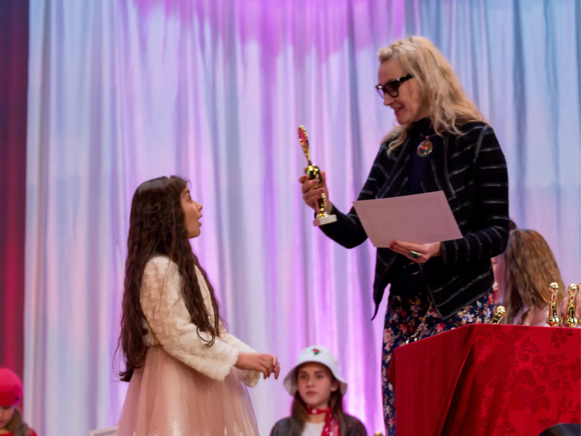 Juliana Polansky presenting a trophy to a young performer at a student showcase