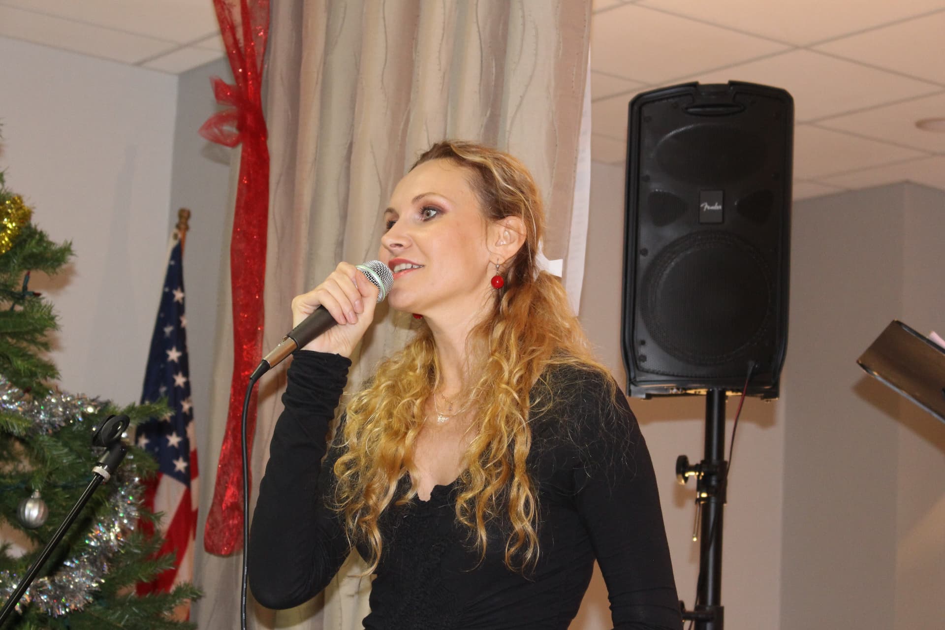 Juliana Polansky singing into a handheld microphone at a holiday performance